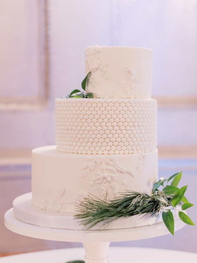 white staircase cake with greenery accents