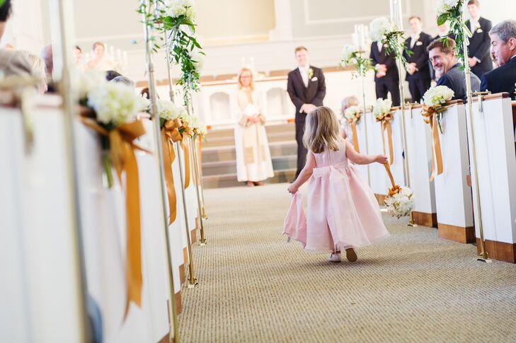 The flower girl wore a pink A-line dress with a bow in the back and carried a white daisy pomander down the aisle.