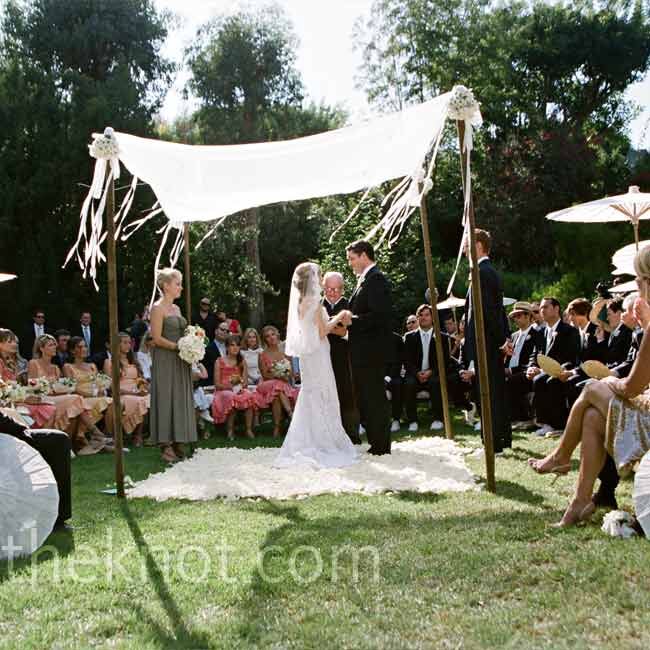 Guests sat or stood in a circle around Courtney and Andrew for a more intimate feel. The couple stood on a blanket of white rose petals, beneath four bamboo poles draped with white fabric.