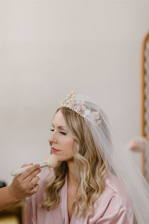 Bride in a Pink Robe, Crown and Long Veil Getting Makeup Done