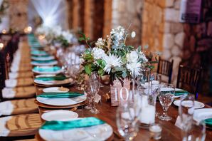 Long Wood Table, Low Centerpieces With White Flowers and Greenery, Wood Table Numbers, Gold and White Chargers, Turquoise Satin Napkins at Wedding Reception