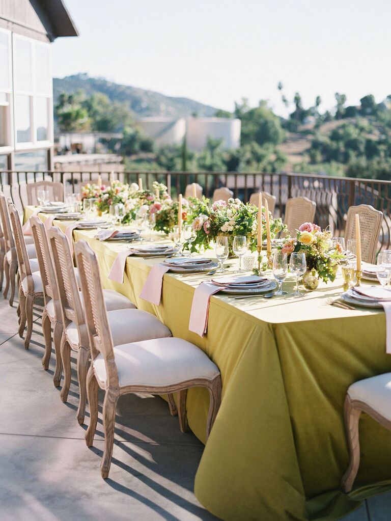 Outdoor summer wedding tablescape with yellow and pink linens and florals