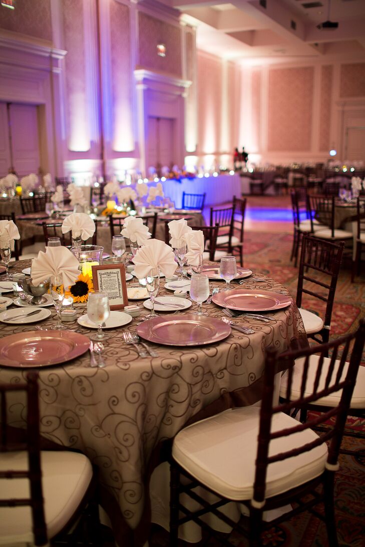 The indoor reception at Founders Inn was illuminated with purple uplighting. The tables were set with embroidered brown linens and chiavari chairs.