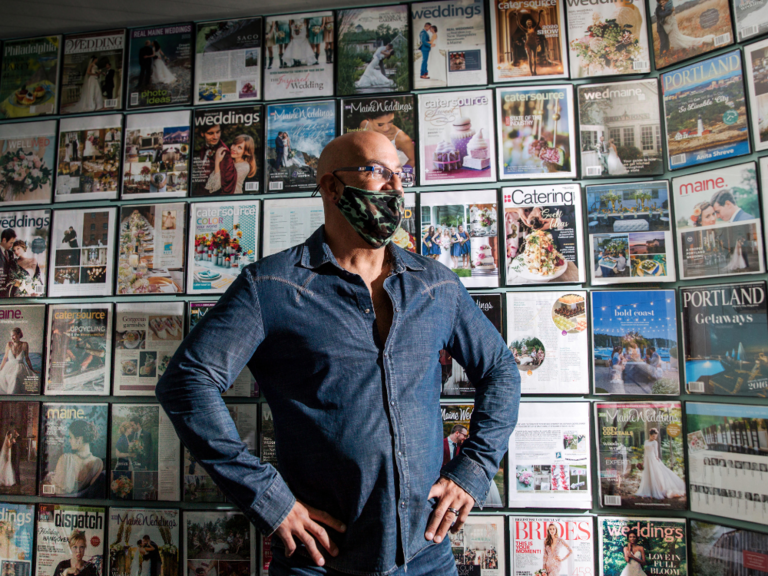 man posing in front of wall filled with magazines