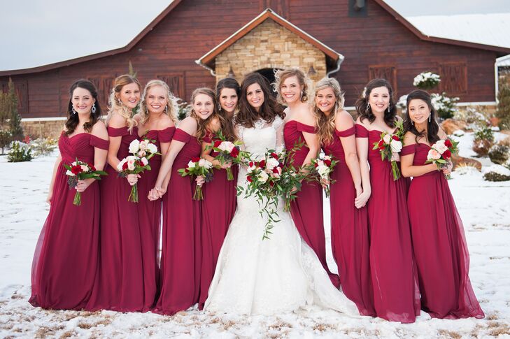 The bridesmaids were dressed in glamorous floor-length, bourdeaux off-the-shoulder dresses. Each carried a similar bouquet to the bride full of roses, greenery and pivot berries.