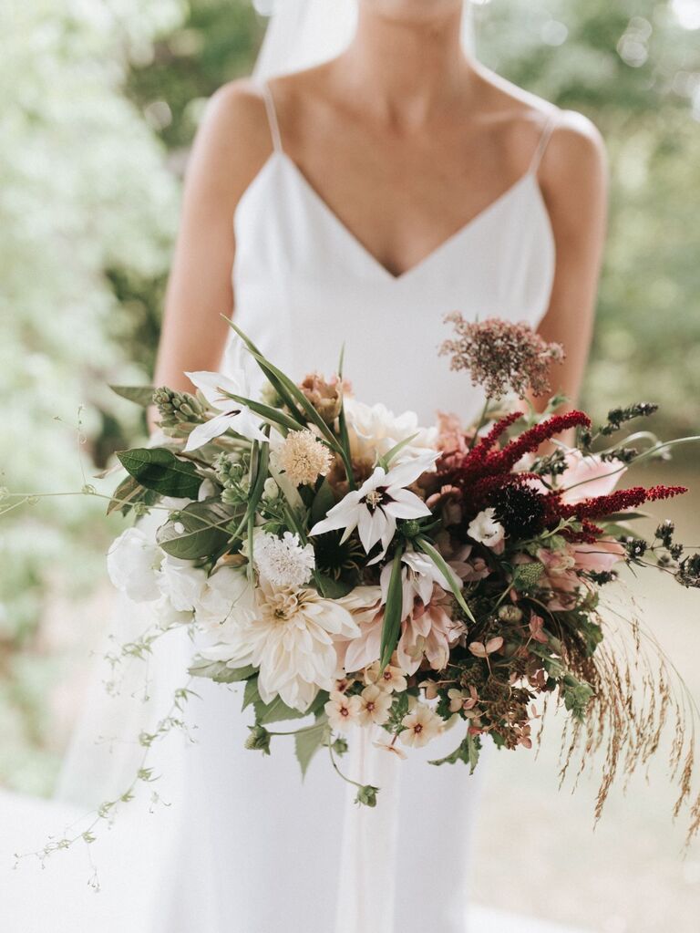 Bride holds a beautiful bouquet of cafe au lait dahlias and greenery. 