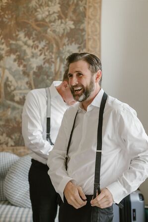 Groom Getting Ready and Putting on Suspenders for Classic Tuxedo Look