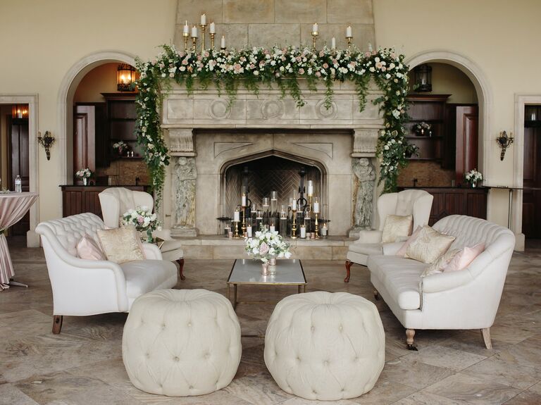 wedding lounge area with fireplace in the background decorated with greenery and gold candlesticks