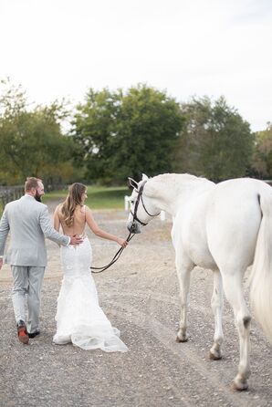 Groom in Light Gray Suit and Bride in Fitted, Low-Back Gown Walk White Horse