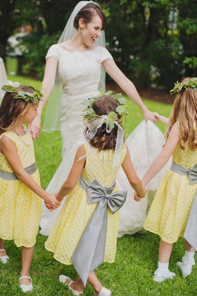 Bride in fingertip-length veil dancing with flower girls 