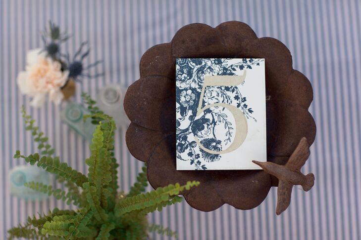 White stationery were designed with navy blue floral patterns, and had a table number depicted in gold.