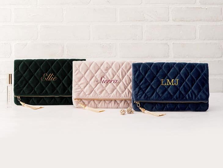 Three velvet fold over clutches in green, blush, and navy, with tassle zips and personalized names from The Knot Shop