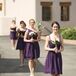 The bridesmaids wore eggplant purple dresses in different styles, while carrying simple, romantic bouquets wrapped in burlap.