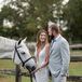Bride and Groom in Formal Attire on a Ranch With the Bride's White Horse