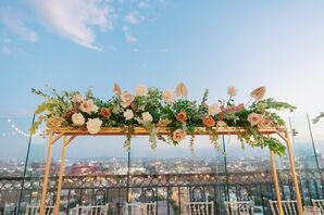Tall, Suspended Floral Centerpiece of Neutral Blooms on a Gold Structure at Rooftop Reception