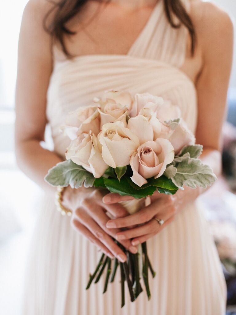 A bridesmaid holds a bouquet of pale pink roses.