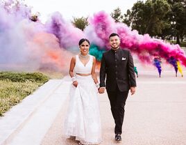 Couple on their wedding day with colorful smoke behind them