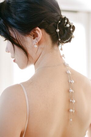 Bride With Low Bun Updo and Long String of Pearls Tied Into Hair, Unique Accessory