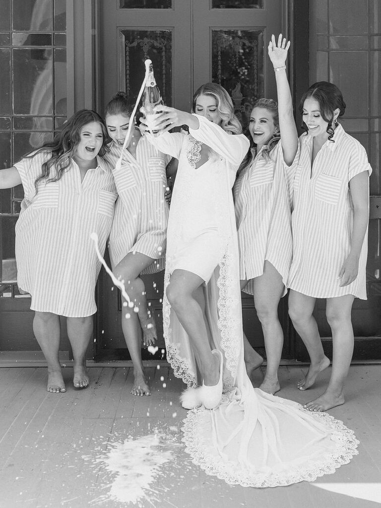 Bride pops champagne while bridesmaids cheer. 
