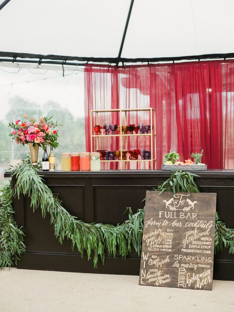 wedding cocktail bar decorated with greenery garland and colorful flower arrangement