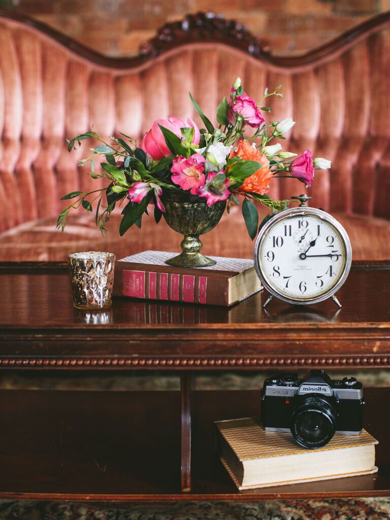 Vintage wedding decoration vignette with heirloom clock, candle, bouquet of flowers and antique book