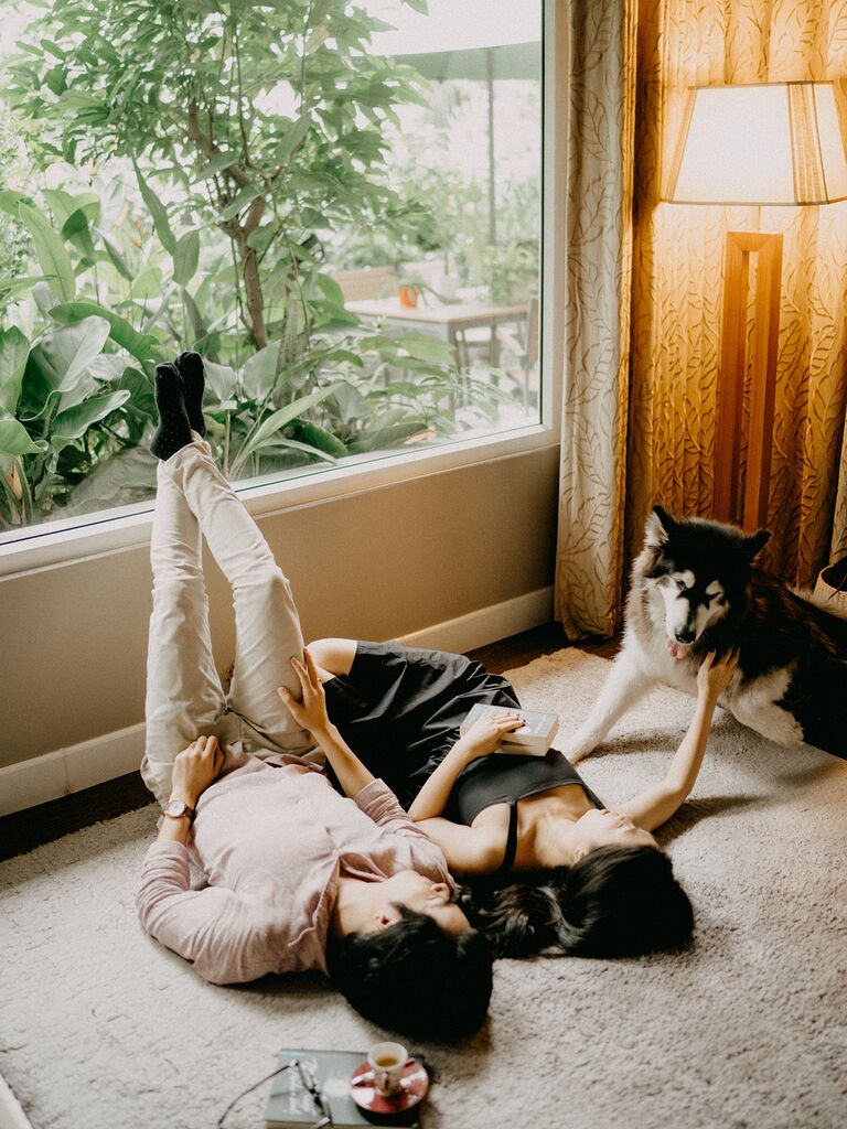 Couple pose in their cozy apartment with their dog. 