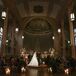 Dimly Lit Ceremony With Lots of Candles, Stained-Glass Windows in the Round