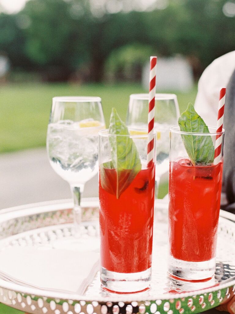 strawberry cocktails with red and white striped paper straws on a tray
