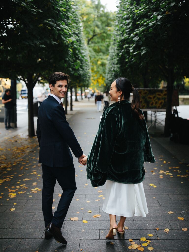 A couple walks down a tree-lined path for their engagement photo