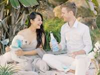 Couple sharing champagne toast on the beach with their dog
