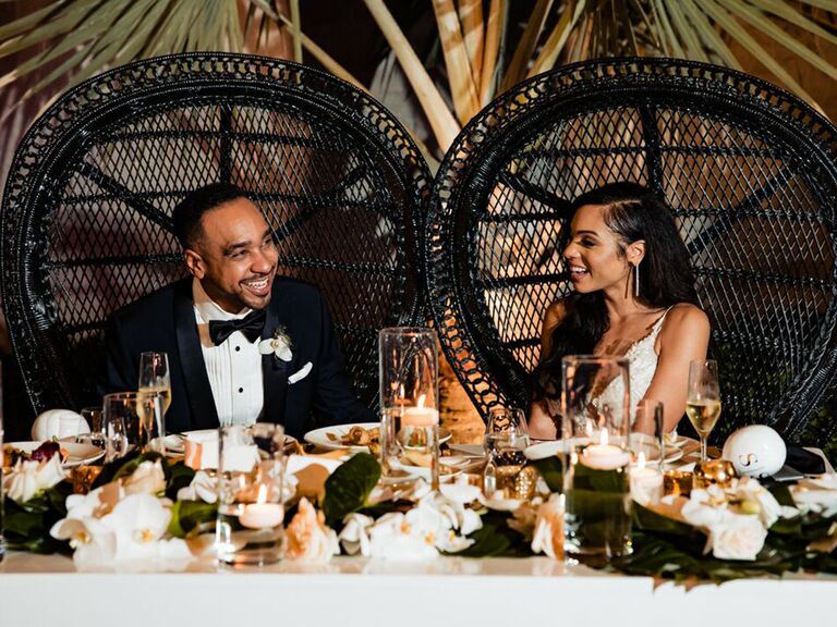 groom and bride seated on chairs and smiling at each other