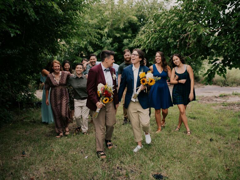 Couple holding sunflower bouquets with wedding party