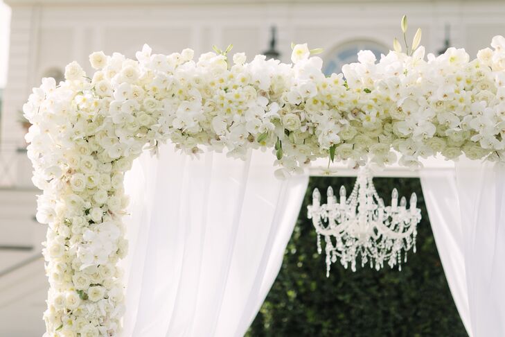 The couple shared a first kiss under a white flower arch made from bunches of fresh orchids and roses.