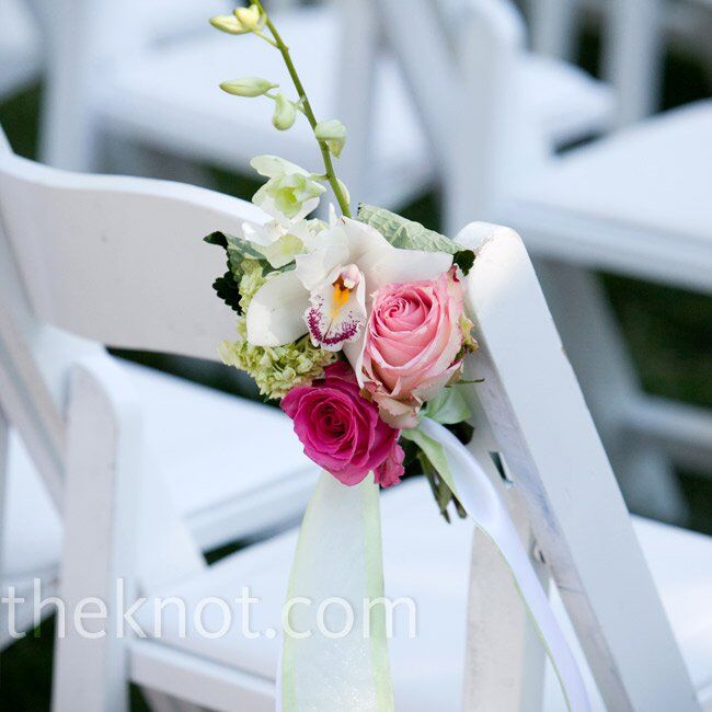 Petite arrangements of roses and orchids decorated the aisle chairs at the ceremony.
