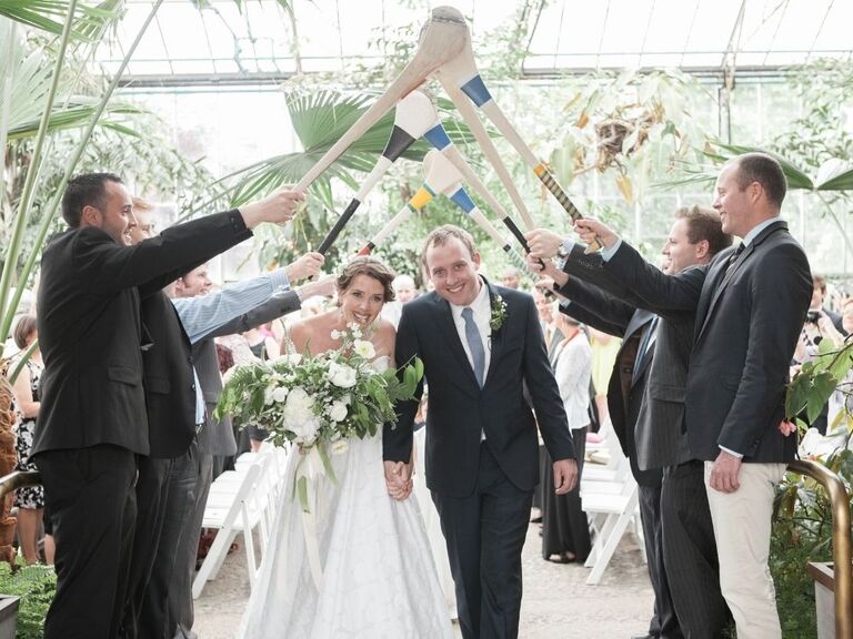 couple exiting Irish wedding under tunnel of hurley sticks