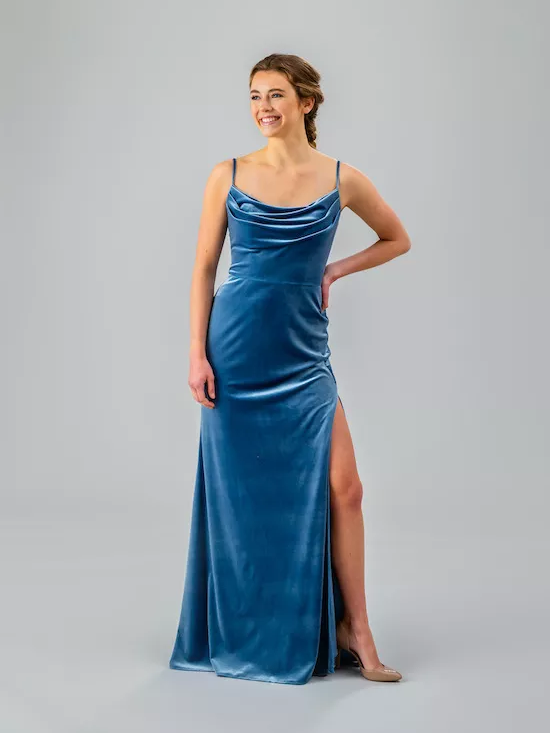 A model wears a shimmery-soft blue bridesmaid gown with a cowl neckline and slit.