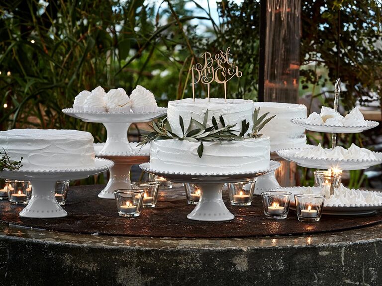 Outdoor woodland wedding dessert spread with cakes on white pearl-trim cake stands