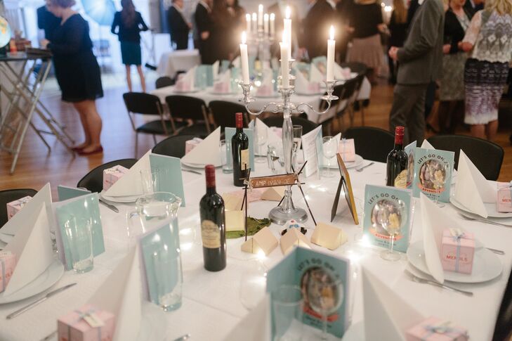 At the center of each dining table was a lit silver candelabra. One of the dining tables had a centerpiece that resembled Camp Ivanhoe from 'Moonrise Kingdom.' The reception programs and menus also reference 'Moonrise Kingdom.'