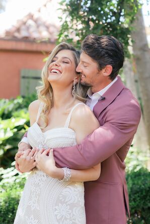 Couple Embracing in Pink Suit and Boho-Chic Wedding Dress at Spring Wedding