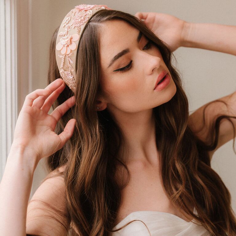 Model wears a pale pink headband with floral embellishments. 