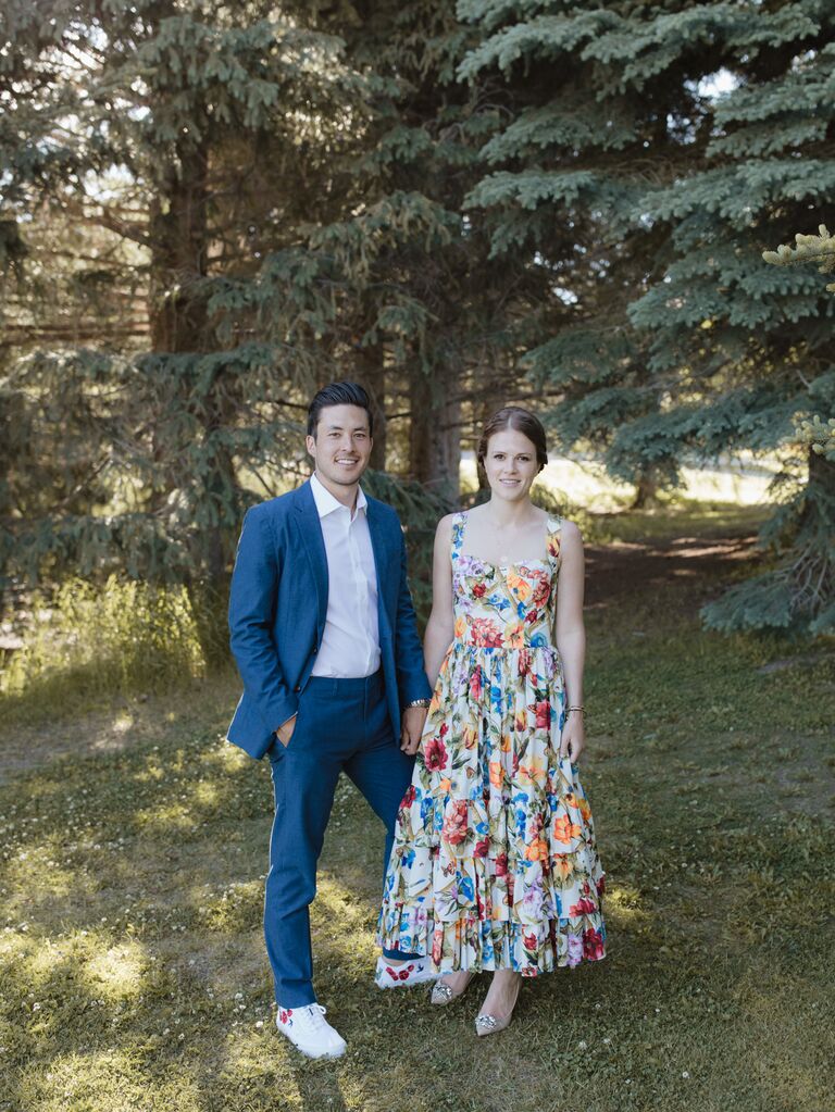 The happy couple stand together beneath the trees