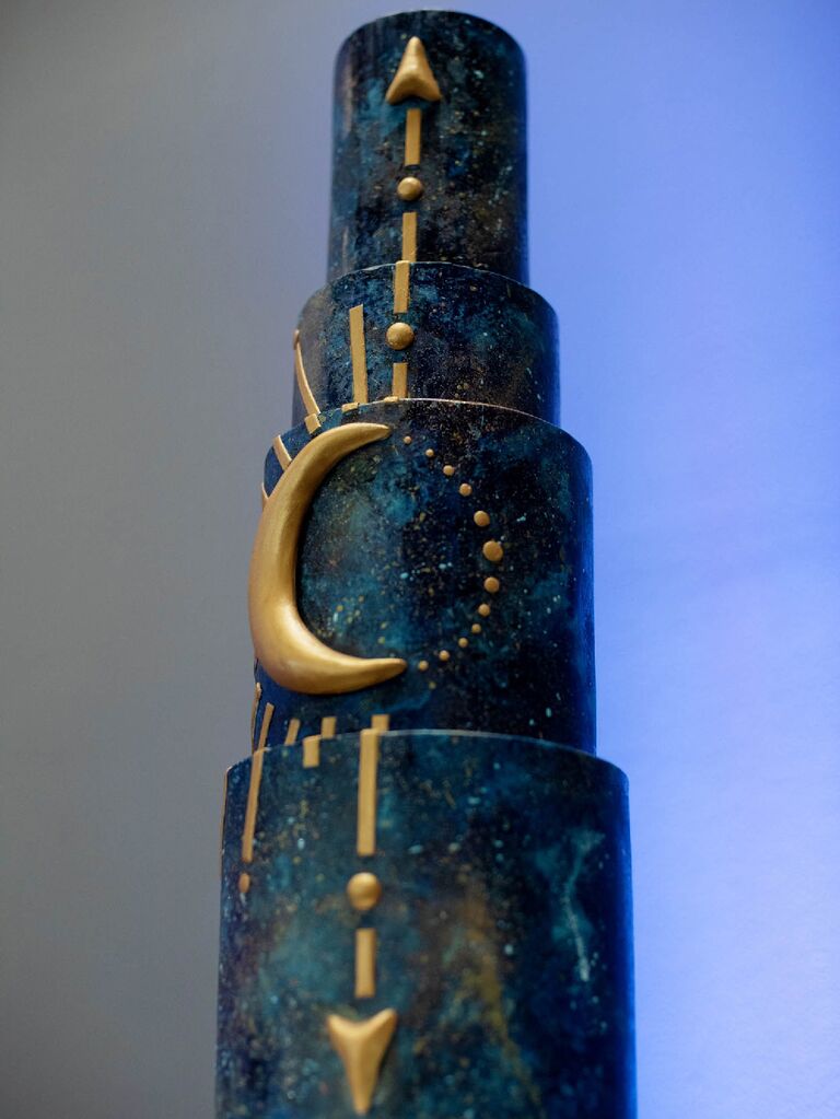 Galaxy-inspired celestial wedding cake with dark blue base and gold moon and sunburst accents