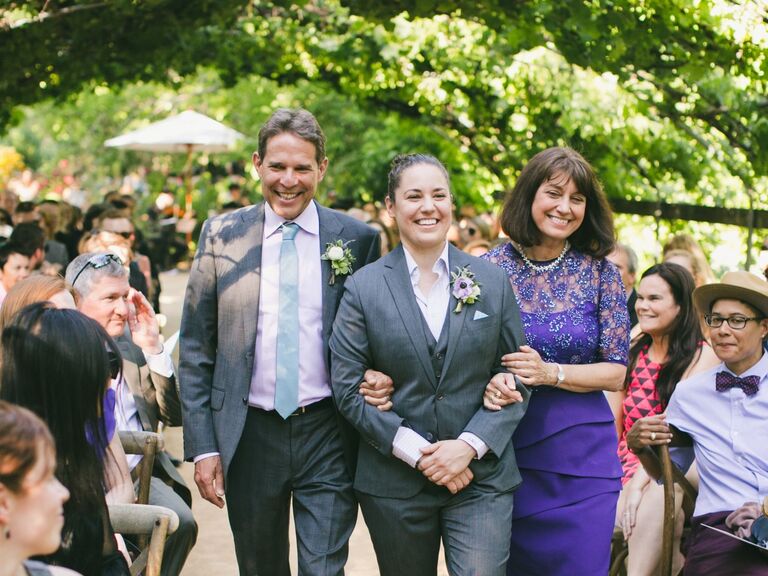 Parents of the bride walk down the aisle arm-in-am with their daughter. 