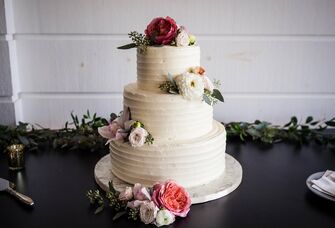 white three tier buttercream wedding cake with pink and white flowers