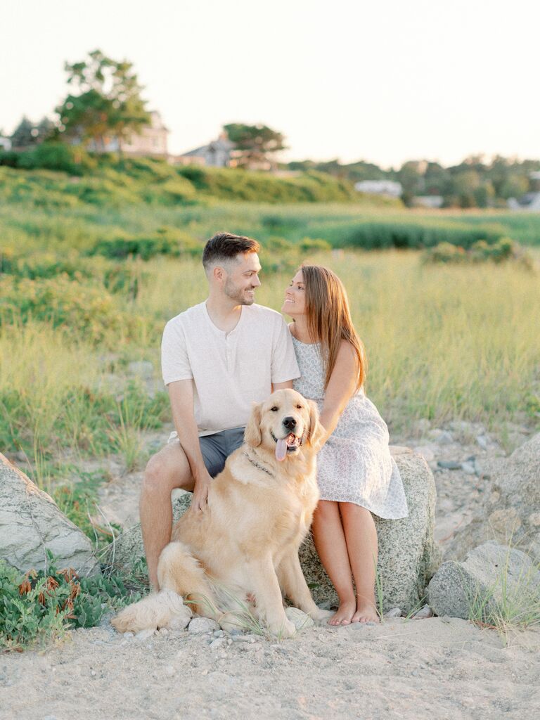 Couple pose on the beach with their dog. 