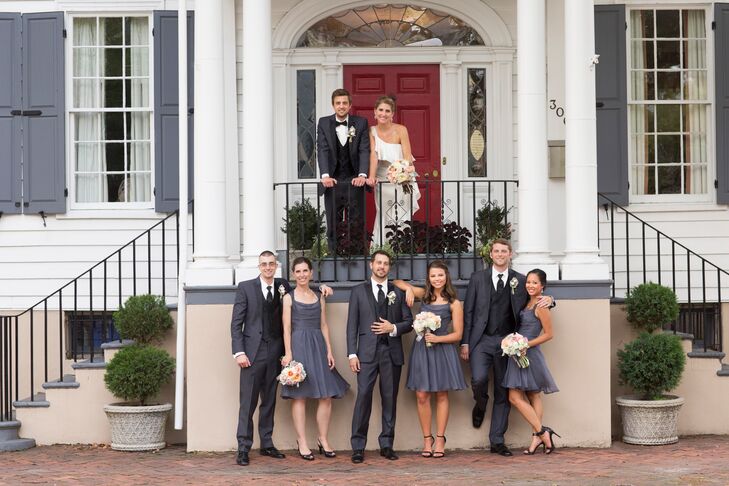 To compliment the groomsmen's charcoal gray tuxedos, the bridesmaids wore gray, A-line chiffon bridesmaid dresses that hit at the knee with black heels. Their bouquets were smaller versions of the bridal bouquet and included roses, ranunculuses and dusty miller. The wedding party is standing in front of the house where Beth's great-grandfather once lived.