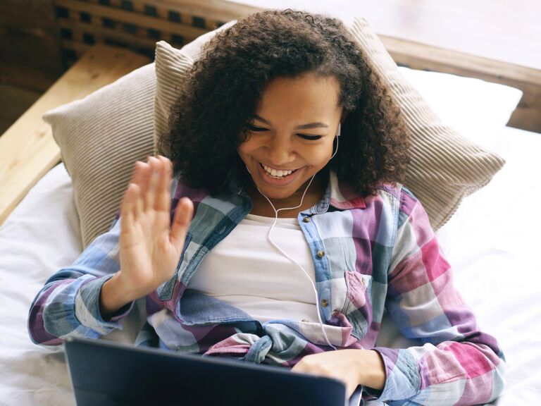 Woman waving to friend on laptop video chat 