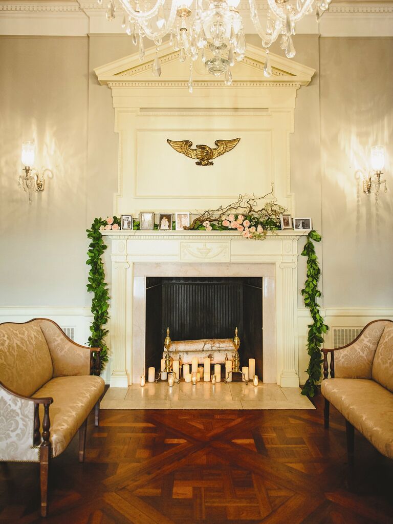 classic wedding fireplace decor idea with greenery garland and framed family photos along the mantel