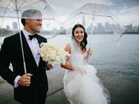 Bride and groom holding umbrellas 