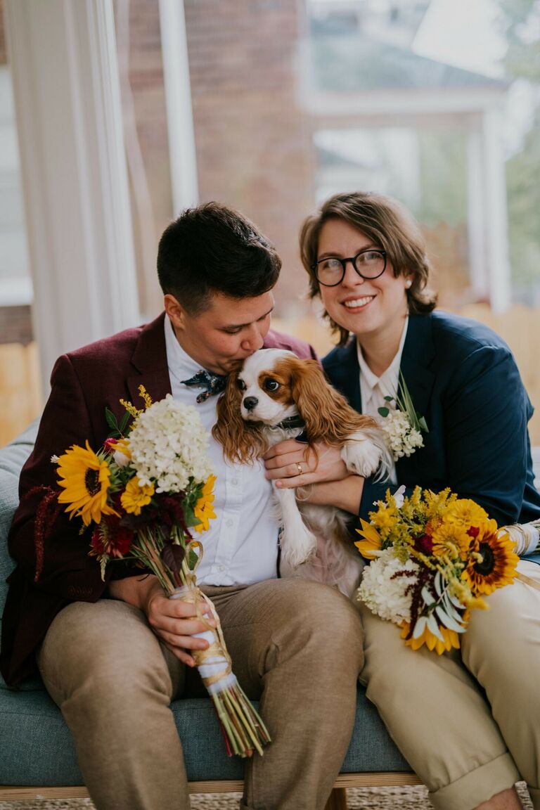 Couple posing with dog and sunflower bouquets